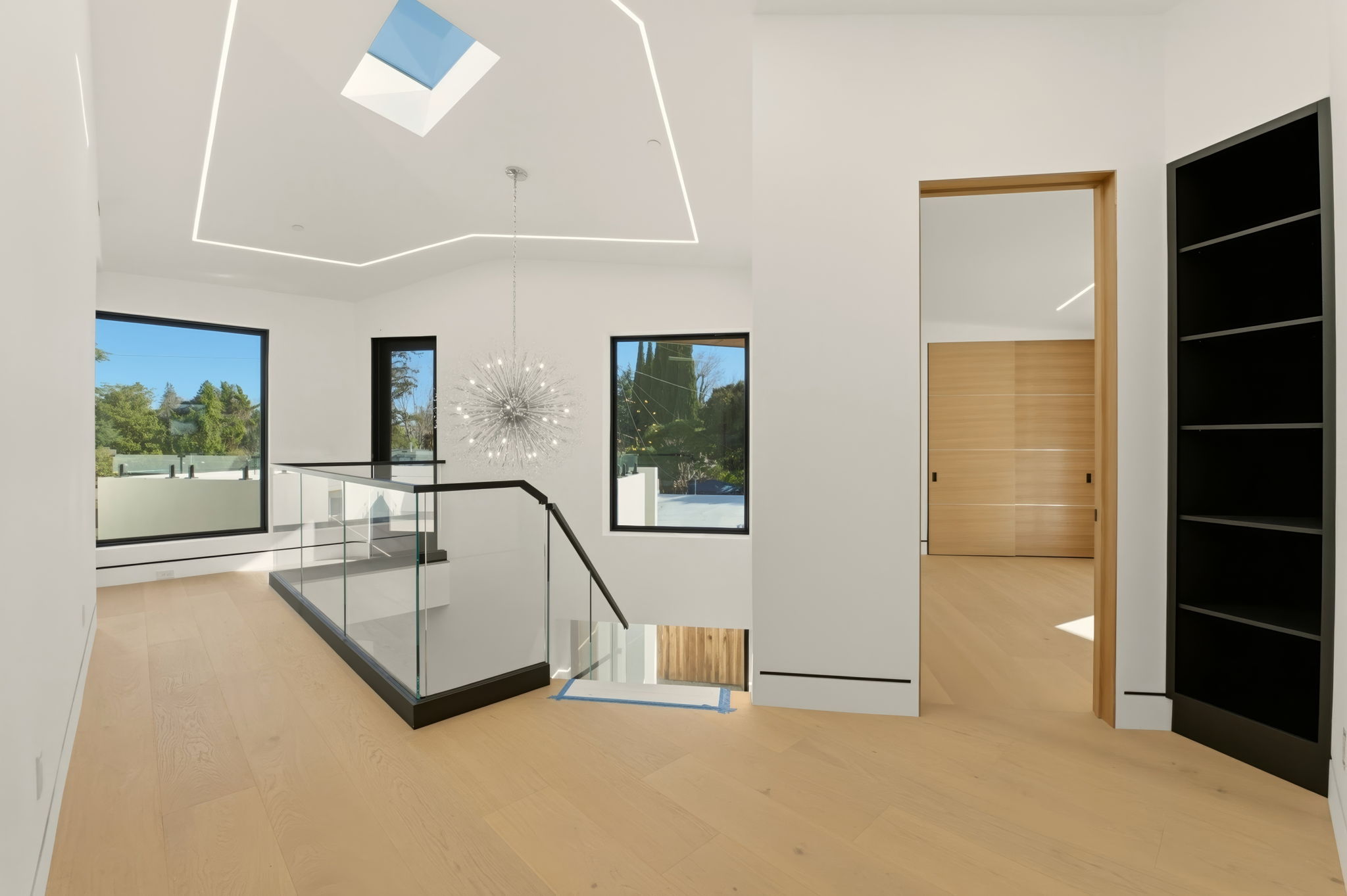 Skylight, sputnik chandelier, trimless natural wood doors